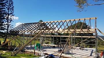 Steel and timber roof frame on a new build against a blue sky